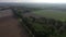 POV from drone flight backwards over trees and agricultural land with a view of a city in the background