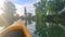 POV: Golden summer sunbeams shine on canoe as you paddle along tranquil stream