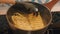 POV hands cooking instant noodle soup at home. Female hand putting dry noodles into boiling water in a pan at home and