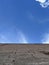 POV Looking at the blue sky with few clouds, at the base of the image a gray wall of rustic blocks