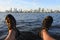 POV of person sitting on Swan River riverbank looking at the landscape view of  Perth city financial centre skyline at sunset