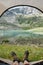 POV selfie shot of mans feet in trekking boots against majestic landscape of mountains and lake