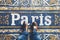 a pov shot looking down on a persons feet standing on a mosaic tiled floor with the word Paris