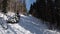 POV from Ski Chair Lift Between Pine Forest and Skiers Rising up on Cableway