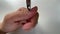 POV view of cuticle nippers cutting out old cuticle off the finger nail. Close-up manicure treatment process at white