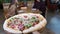 POV Waiter Brings Pizza Out on Wooden Tray to Restaurant Customers. Slow Motion