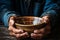 Poverty personified old mans hands, empty bowl, wood backdrop symbolizing destitution