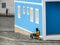 Povoacao Velha, Boa Vista, Cape Verde, Africa - February 9, 2018: A man sits on the street against a blue house wall