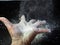 Powder on hands,White flour flying into air on black background