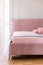 Powder pink double bed with light blue blanket standing in real