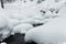 Powder snowdrifts on the stones of mountain river and forest snowfall