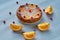 Powdered citrus pie with caramelized oranges and fresh red berries on the gray table. Orange pie decorated with raw orange slices
