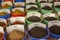 Powdered and dried spices in large bowls with names stand in rows on the counter