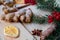 Powdered ginger with dried orange, anise, raw red berries close up on wooden table. Decorated with blurred Christmas tree branch