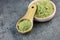 Powdered matcha in bowl and wooden spoon on dark background - medicine alternative