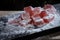 Powdered sugar is sprinkled on berry marmalade jelly candy's on wooden cutting board on a black background