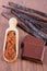 Powdery cocoa, dark chocolate, fragrant vanilla sticks on wooden surface