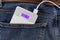 Power bank with connection USB cable in the back pocket of the jeans closeup