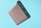 Power bank pale pink color on a blue background. External battery for gadgets. Levitation of objects