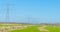 Power line in a green field in wetland in a blue sky in springtime
