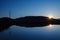 Power line in mountains and sunset reflected in a calm lake