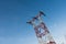 Power line tower standing against blue summer sky