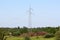 Power line utility pole with wires connected with transparent glass insulators next to hunting observation tower and cut down logs