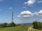 Power lines across mountains landscape, blue sky, green fields and path. Energy industry. Copy space