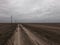 Power lines along a dirt road. Gloomy evening landscape