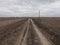 Power lines along a dirt road. Gloomy evening landscape