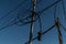 Power lines, electric poles with black straight and twisted wires and small transformer bank. Backdrop blue gradient