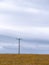 A power lines in a field, sky. Minimalistic landscape, electric post on grass field, cloudy sky