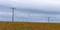 A power lines in a field, sky. Minimalistic landscape, electric post on grass field under cloudy sky