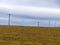 A power lines in a field, sky. Minimalistic landscape, electric post on grass field under white cloudy sky