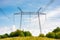 Power lines tower on a meadow against the blue sky