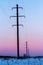 Power lines on winter snowy field at sunset. High voltage electric transmission tower. Nature landscape