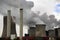 power plant with chimneys and steaming cooling towers, gray clouds rise in the sky