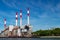 Power plant smoke stack towers contrast against blue sky