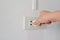 Power saving concept, Hand plug and unplug the electric socket on white wall.