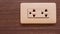 A power socket, white, mounted on a wooden house wall and hidden the wires inside