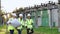 Power specialists are planning a new project outdoors. Three engineers walk near power lines in the high voltage power