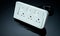 Power strip with three electrical standard socket on black background. White universal plug with overload protection. Fire