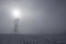Power tower current distribution lines, in winter snowy countryside in a misty atmosphere