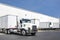 Powerful day cab big rig white semi truck tractor hooks a loaded dry van semi trailer in warehouse dock gates area