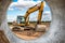 Powerful excavator at the construction site. View of the excavator through the pipe. Close-up of earthmoving machinery.