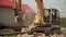 Powerful excavator shovels debris with bucket in dust cloud