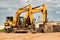 Powerful excavators at a construction site against a blue cloudy sky. Earthmoving construction equipment. Lots of excavators