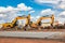Powerful excavators at a construction site against a blue cloudy sky. Earthmoving construction equipment. Lots of excavators