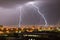 Powerful flash lightning hitting the city at night over dark gray sky. A strong lightning strike over hits the ground