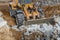 A powerful front loader on a construction site clears up the battle after dismantling reinforced concrete structures. Moving soil